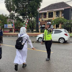 Polsek Rasanae Barat Laksanakan Rawan Pagi, Bantu Pelajar Menyeberang Jalan